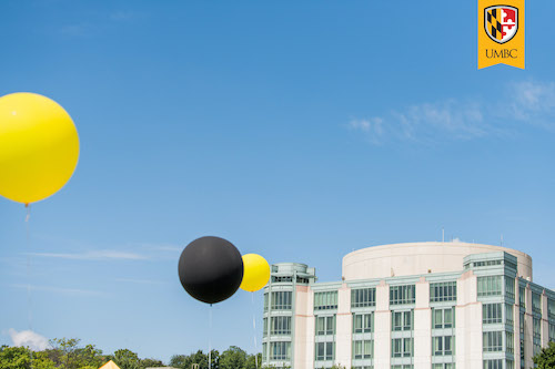 Exterior of UMBC library with row of gold and black balloons in foreground.