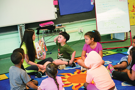 A UMBC STUDENT TEACHER READS TO LAKELAND ELEMENTARY SCHOOL STUDENTS.