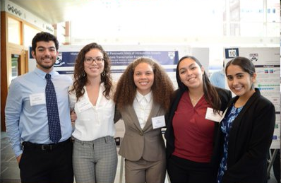 Five student researchers in a brightly lit poster hall.