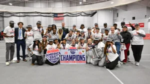 UMBC women's track and field players crowd around an America East Champions sign while celebrating